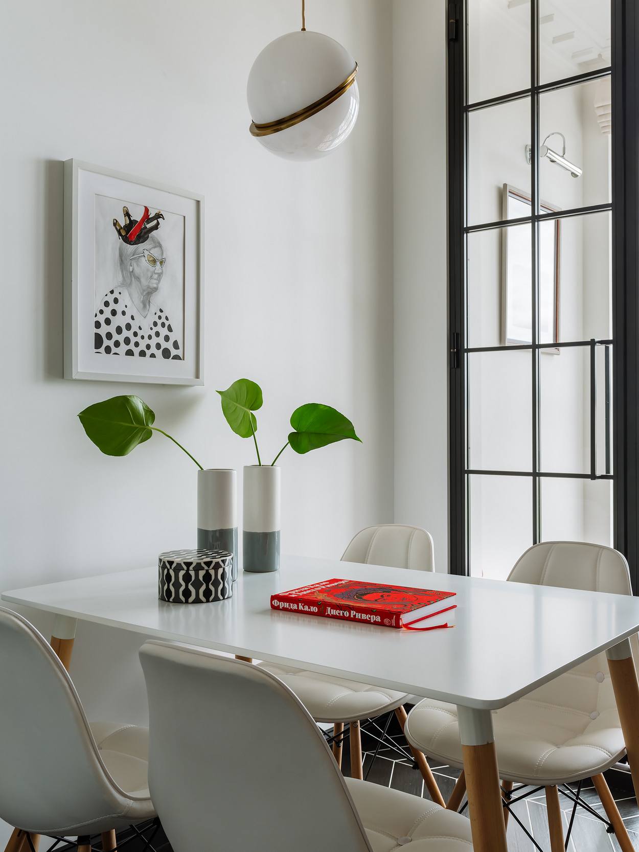 Bộ bàn ghế ở khu vực ăn uống được thiết kế tối giản với bàn trắng hình chữ nhật chân gỗ, 4 chiếc ghế màu trắng đồng bộ đối xứng nhau. Bức tranh cụ già trang trí trên bức tường cũng tạo nên một sức hút khó diễn đạt thành lời.