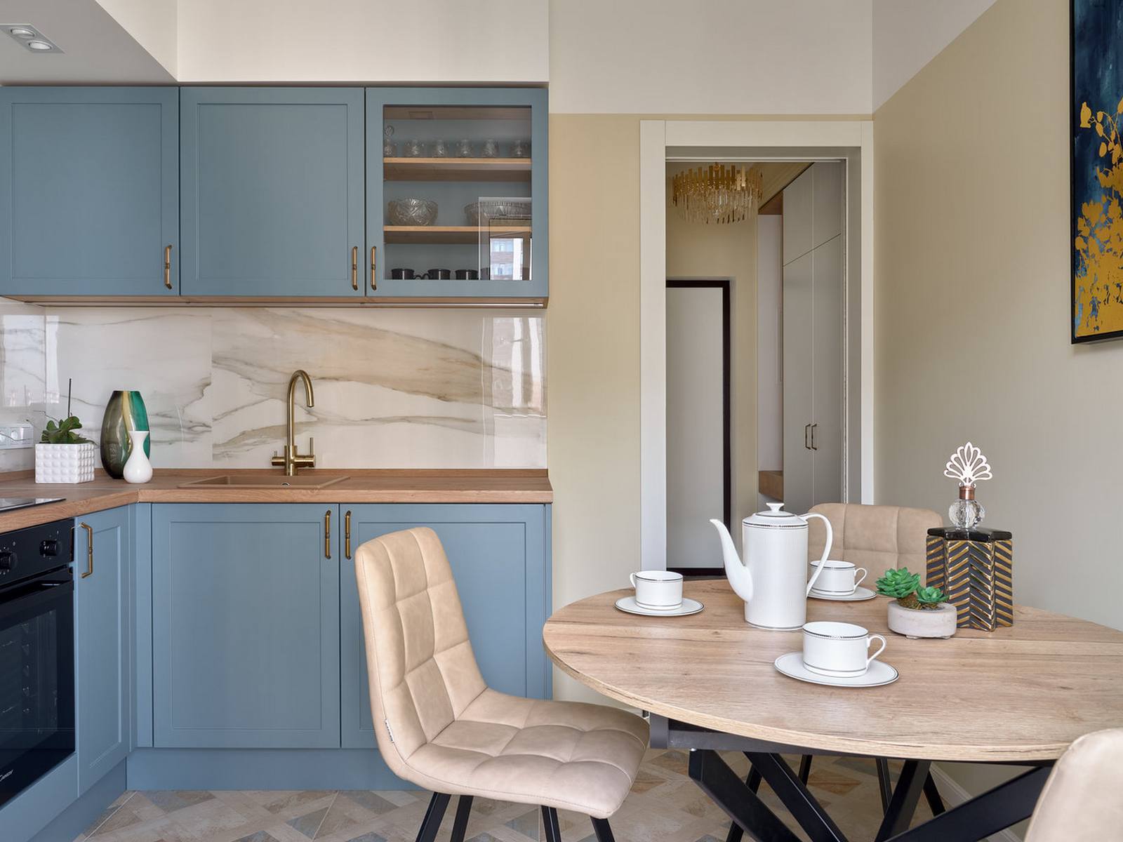 Phòng bếp được thiết kế với bố cục chữ L, với hệ tủ trên và dưới được sơn màu xanh lam, mặt bàn bằng gỗ cùng những điểm nhấn trên vòi nước, tay nắm cửa mạ vàng đồng sang trọng.