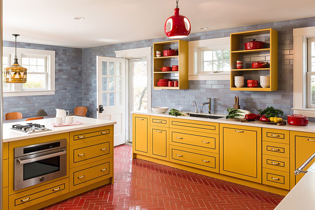 Đỏ và vàng đều là những gam màu 'nóng' nên nhiều người khá e ngại khi kết hợp chúng. Tuy nhiên, phòng bếp này lại hấp dẫn và quyến rũ. Tủ bếp vàng, sàn gạch xương cá, phụ kiện màu đỏ cùng bức tường xám cân bằng lại cảm giác 'nóng bỏng'.