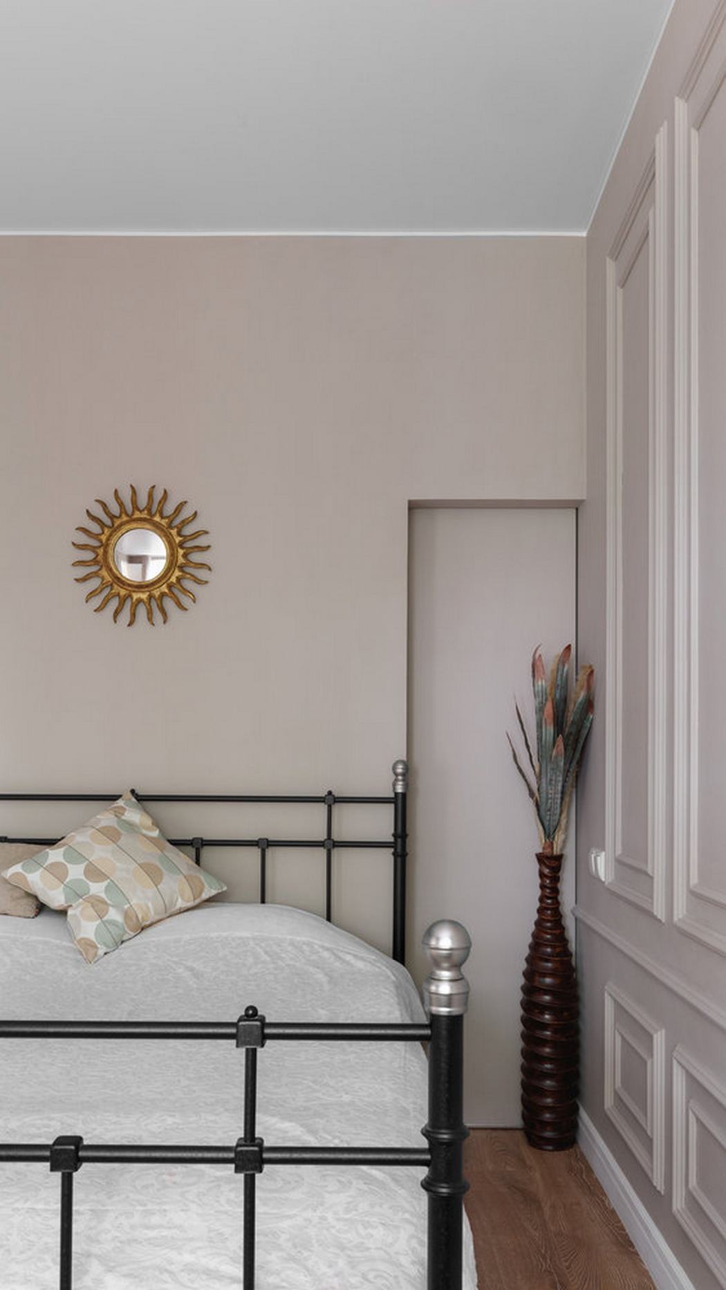 Phòng ngủ là khu vực cần sự thư giãn, yên tĩnh, vì thế nhà thiết kế nội thất đã lựa chọn gam màu be để sơn toàn bộ bức tường, trần nhà màu trắng, khung giường sơn đen và tấm gương tròn như một ông mặt trời nhỏ làm điểm nhấn.