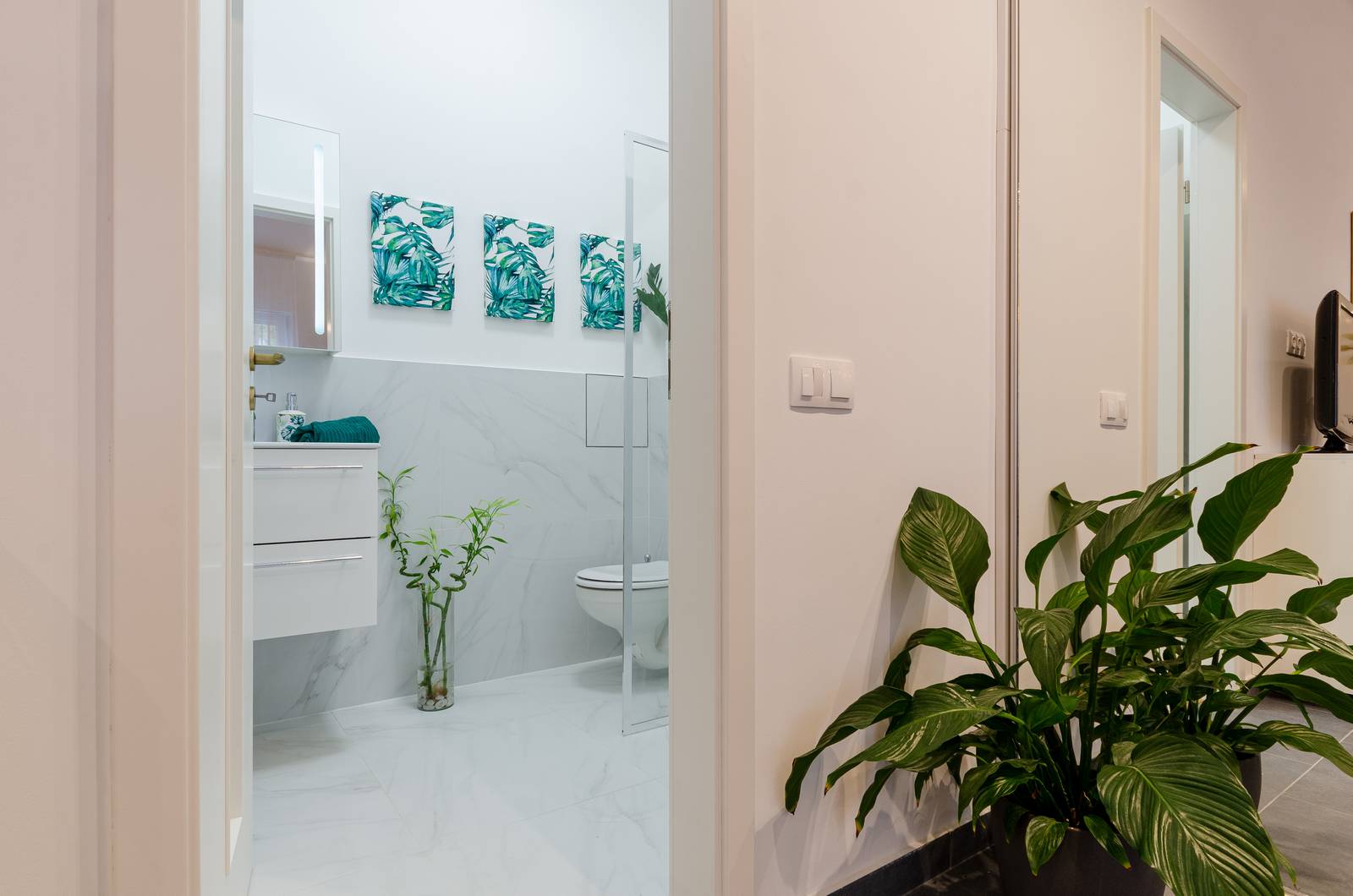 Phòng tắm sử dụng gam màu trắng để sơn tường và gạch ốp sàn cũng như phân nửa bức tường là đá cẩm thạch trắng sang trọng.