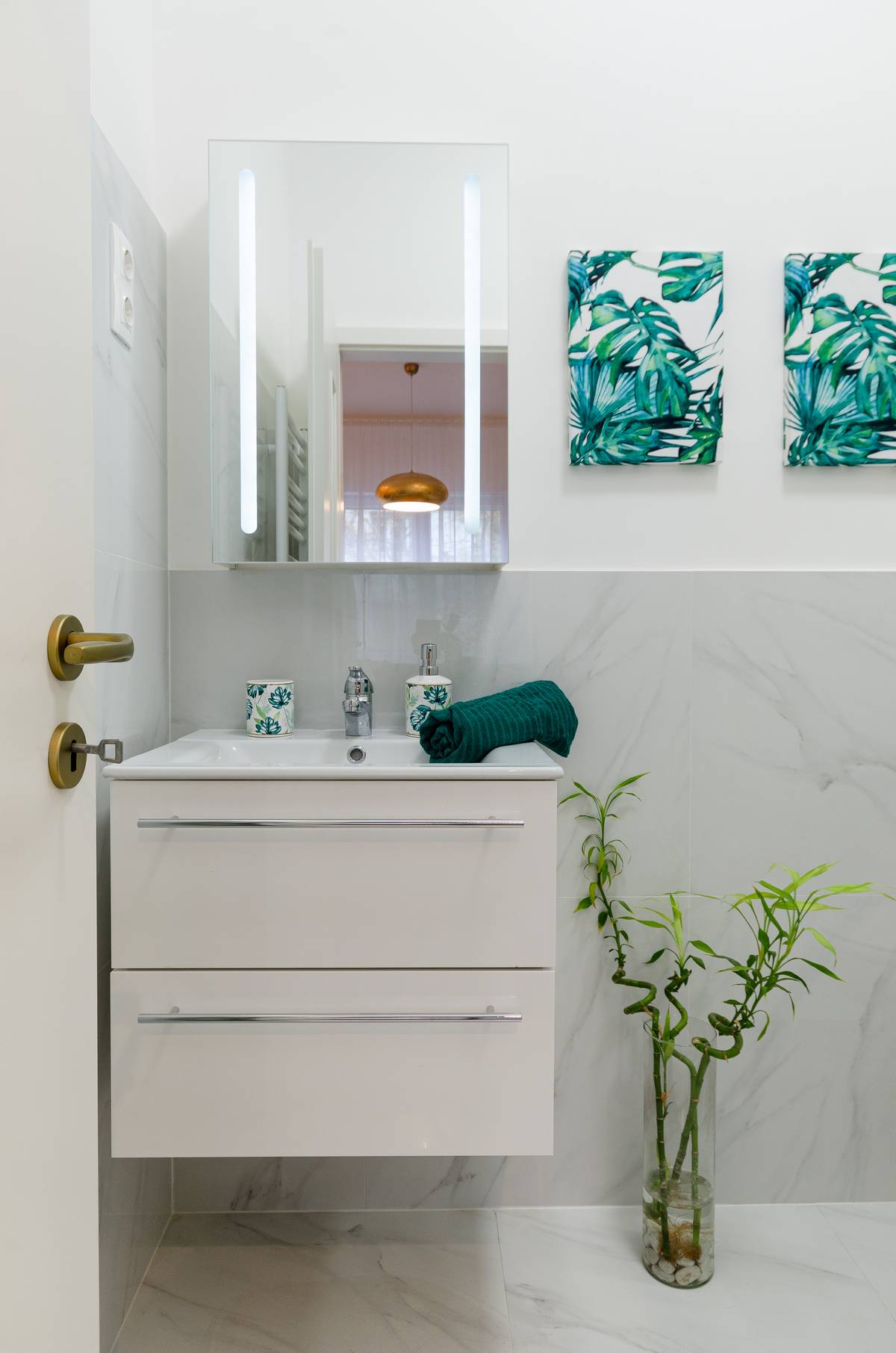Những bức tranh treo tường, cốc nước súc miệng, khăn tắm đều theo xu hướng sắc màu xanh ngọc lục bảo. Một chiếc lọ thủy tinh dáng cao trưng cây trúc cảnh đặc biệt tốt theo quan niệm phong thủy.