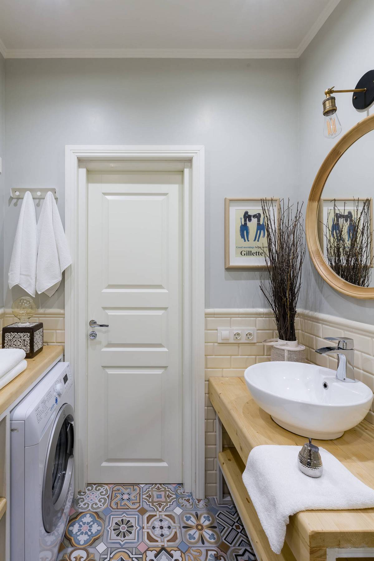 Phòng tắm sử dụng gam màu xám - trắng chủ đạo cùng nội thất gỗ. Sàn nhà lát gạch bông cổ điển tạo sự liên tưởng đến backsplash ở phòng bếp. Chiếc máy giặt được bố trí đối diện bồn rửa một cách gọn gàng.