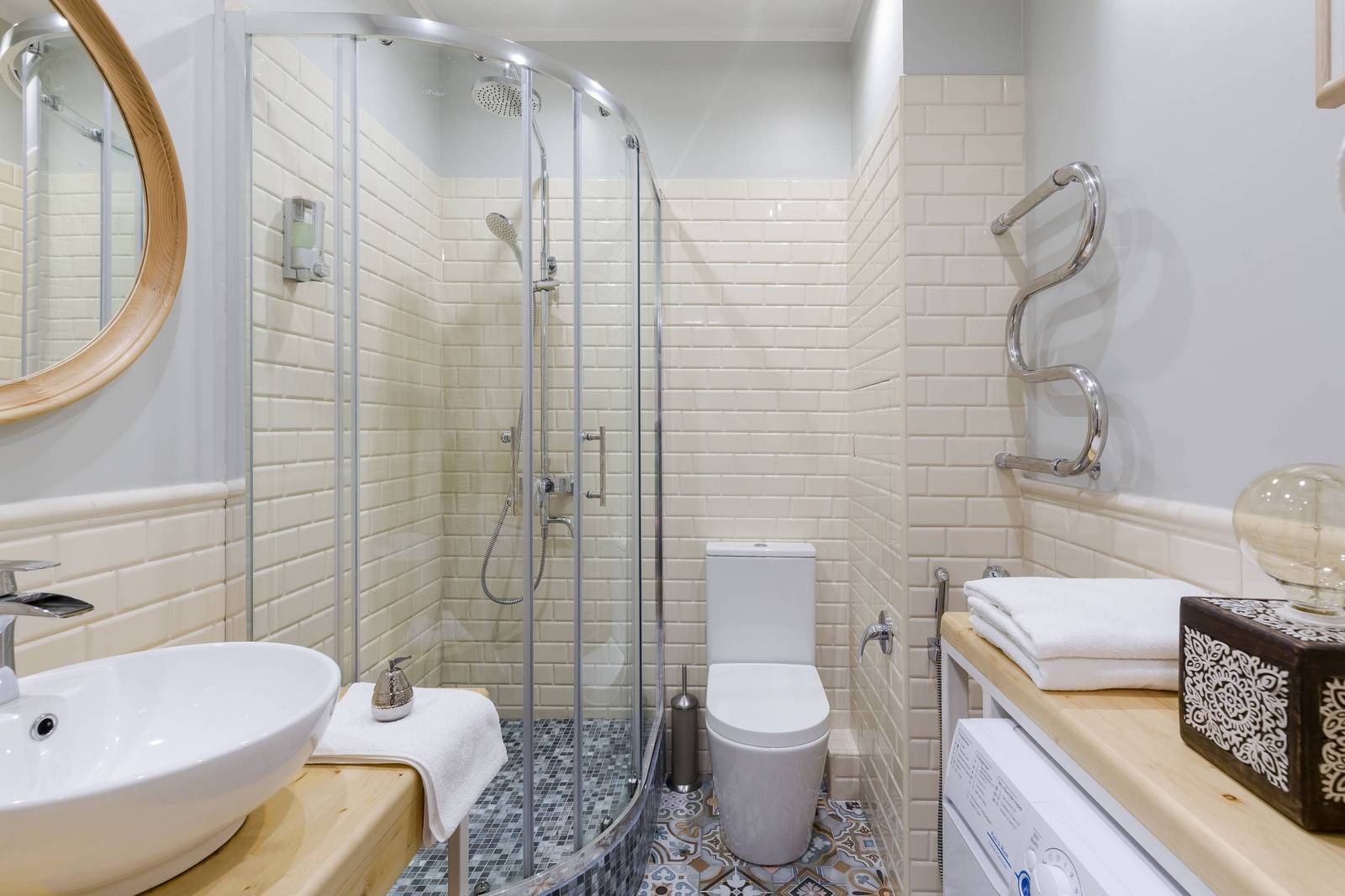 Buồng tắm đứng được thiết kế nâng sàn với cửa kính trong suốt giúp phân vùng với toilet. Gạch ốp tường màu be với độ bóng phản chiếu ánh sáng đẹp mắt, gạch lát sàn buồng tắm cũng có sự khác biệt với tổng thể để tạo điểm nhấn.