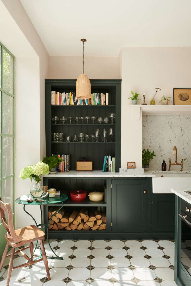 Bước vào bên trong phòng bếp, bức tường màu hồng pastel dịu dàng chiếm trọn trái tim người nhìn. Thay vì sử dụng sắc xanh bạc hà, gam màu xanh ngọc lục bảo đậm được lựa chọn cho kệ lưu trữ và tủ bếp.