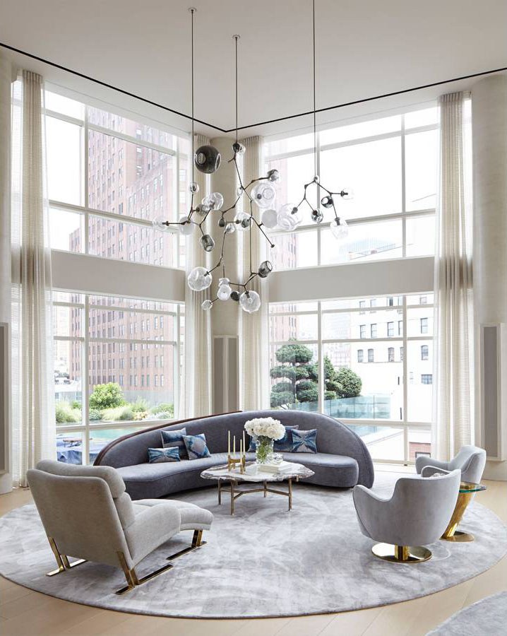 Phòng khách này có ưu điểm là trần nhà cao, kết hợp ô cửa kính trong suốt đón nhận ánh sáng thoáng đãng. Tấm thảm trải sàn hình tròn tạo nên nét tương đồng với sofa cong như 'khoanh vùng' phòng khách.