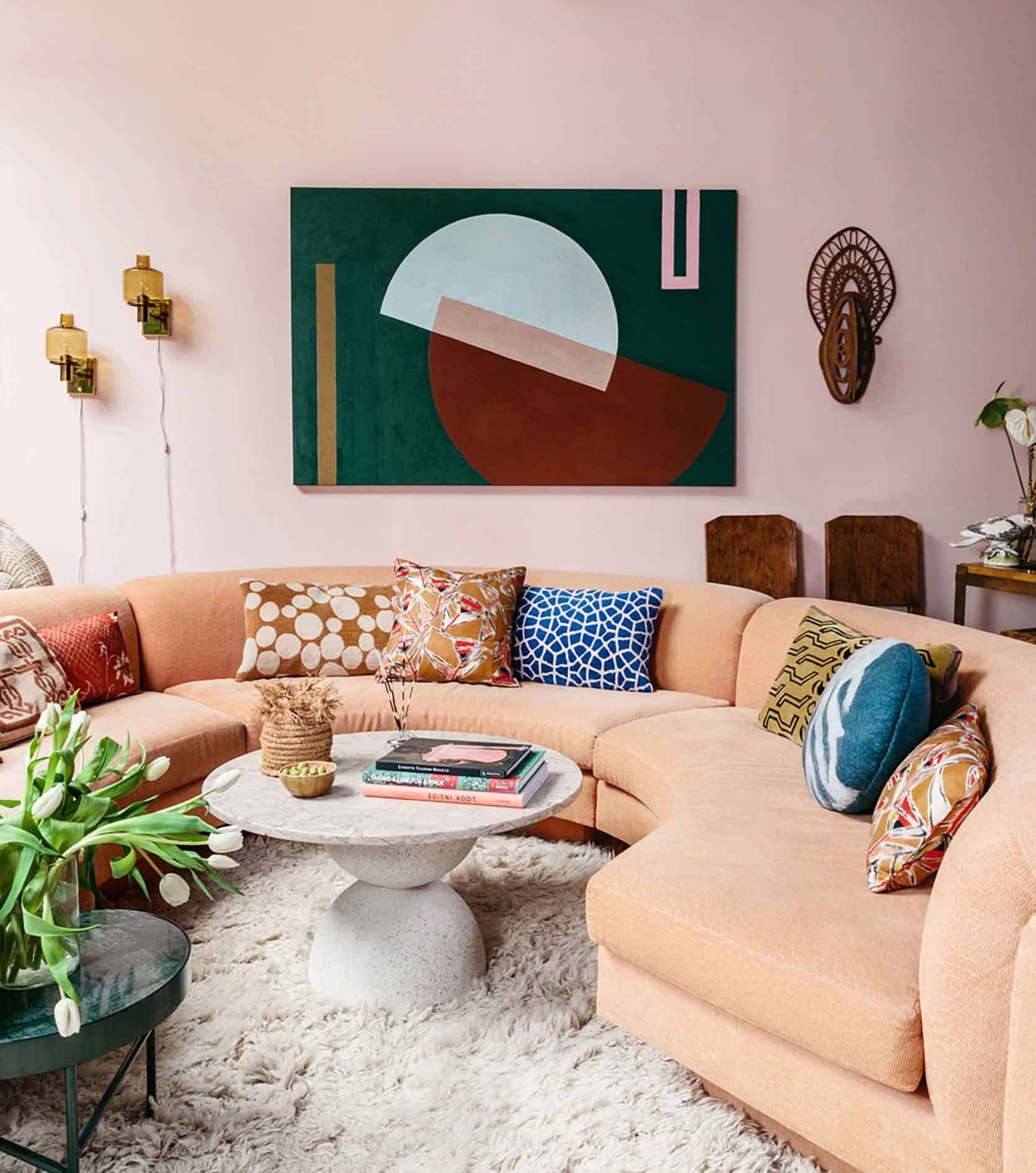 Sofa cong màu cam nhạt trở thành nơi để những chiếc gối tựa đủ sắc màu và họa tiết 'khoe sắc'. Tổng thể phòng khách này cũng rất sống động, tươi vui nhờ sự góp mặt của sắc màu trẻ trung, phong phú.