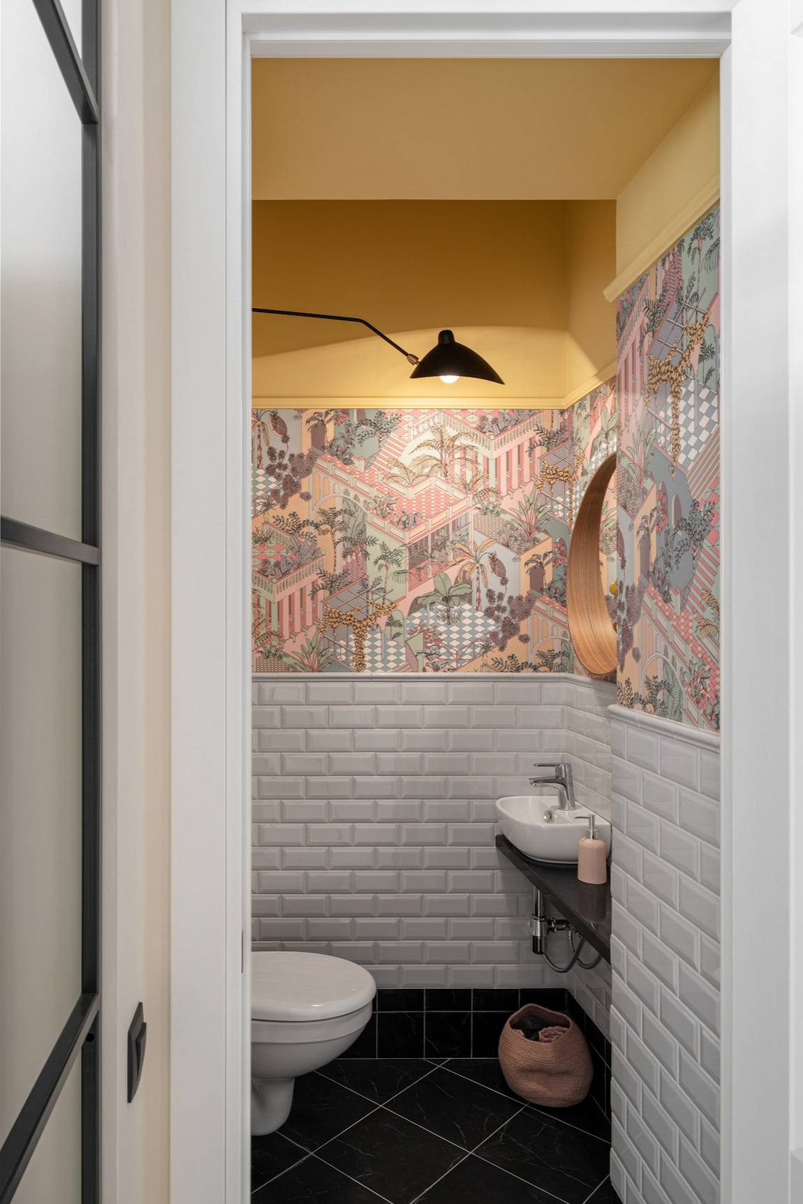 Nhà vệ sinh và phòng tắm được tách biệt thành 2 căn phòng khách nhau do thiết kế ban đầu của căn hộ. Sàn nhà lát gạch màu đen tạo sự tương phản với tấm xốp dán tường giả gạch màu trắng. 