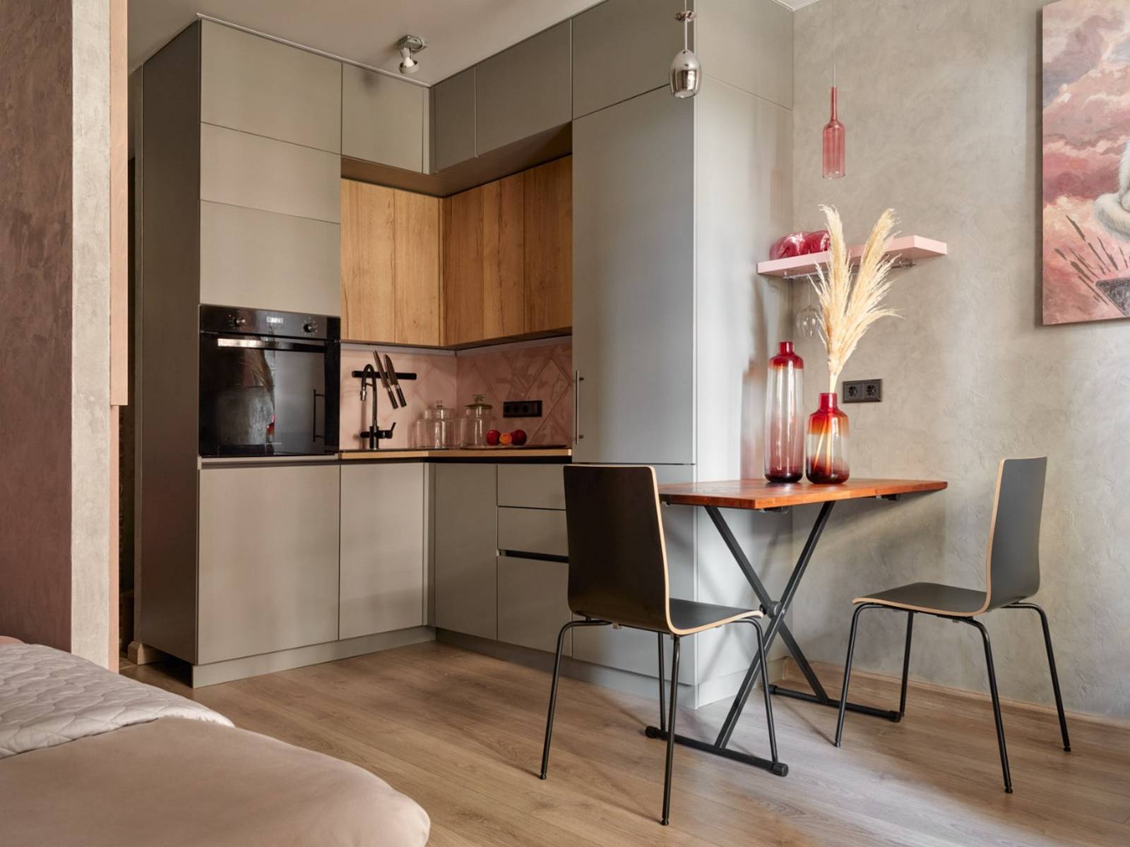 Phòng bếp thiết kế kiểu chữ L phù hợp với cấu trúc căn hộ, toàn bộ hệ tủ bếp có màu xám thanh lịch, kết hợp backsplash màu hồng phấn đẹp mắt. 