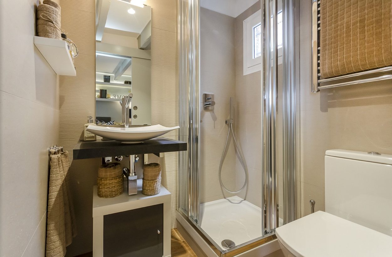 Phòng tắm tuy nhỏ nhưng vẫn đầy đủ tiện nghi cần thiết bao gồm toilet, bồn rửa, kệ lưu trữ, buồng tắm đứng vòi sen phân vùng bằng cửa kính trượt,... 