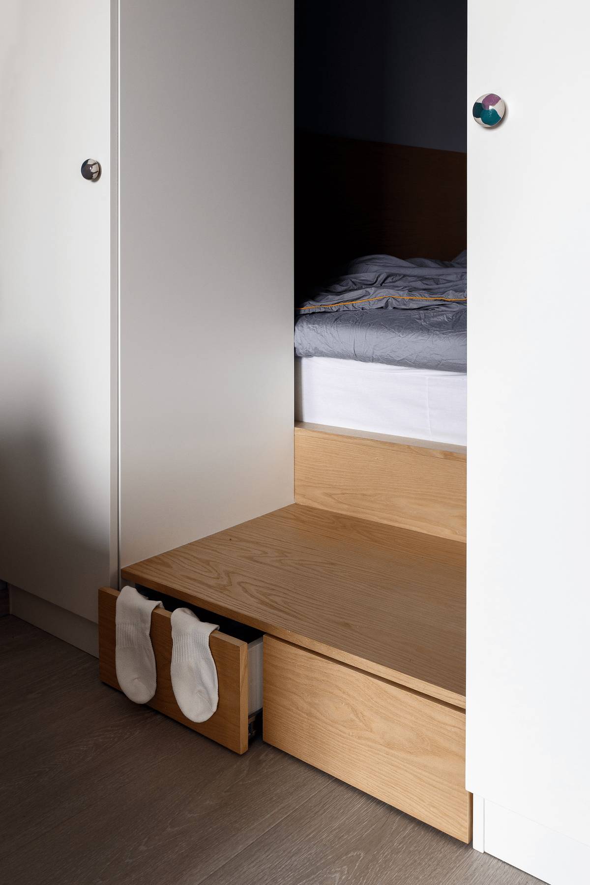Bậc tam cấp gỗ nhỏ nhắn dẫn lối lên phòng ngủ cũng có thiết kế tích hợp hộc lưu trữ tất vớ và những món đồ nhỏ để tối ưu hóa mọi góc trong căn hộ.