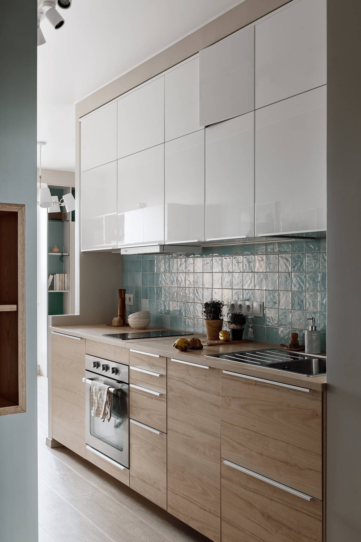 Phòng bếp thiết kế kiểu chữ I nhằm tạo lối đi thông thoáng, hệ tủ bếp trên màu trắng tương phản nhẹ nhàng với tủ bếp dưới bằng gỗ mộc mạc.