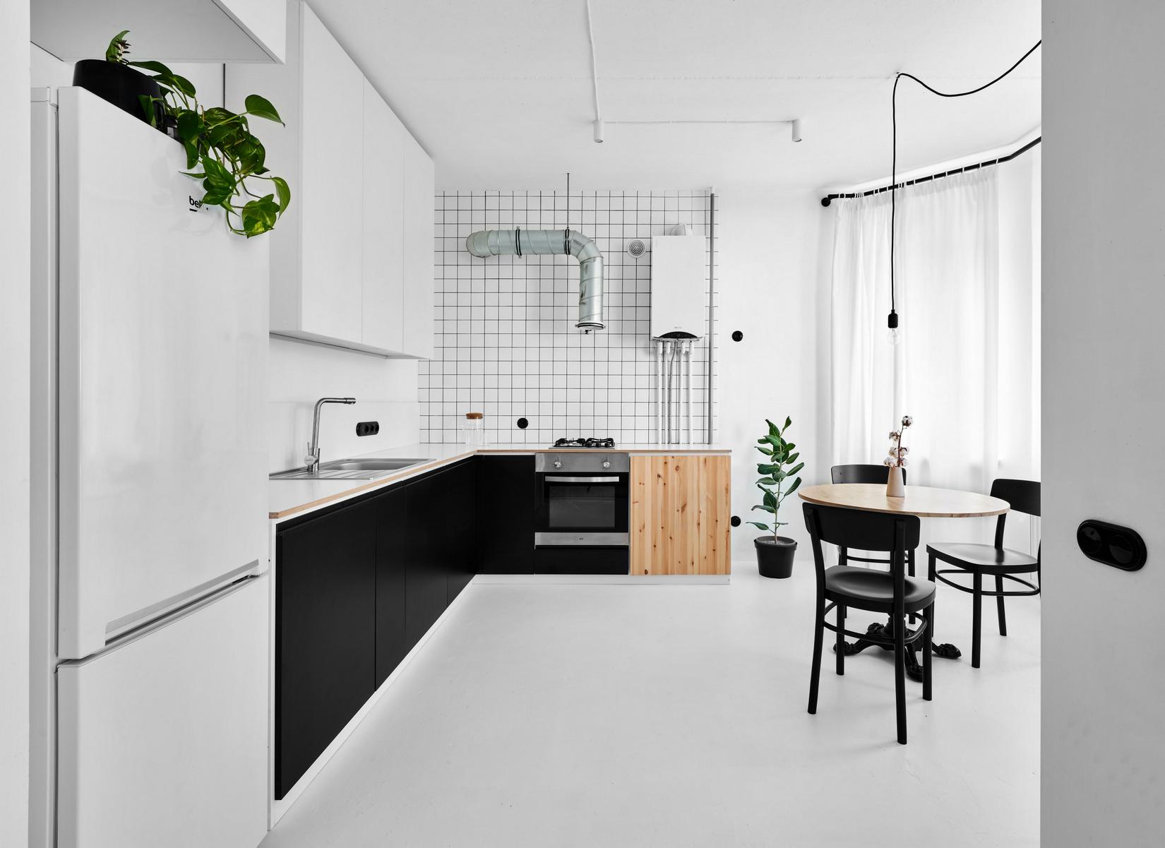 Phòng bếp lựa chọn thiết kế kiểu chữ L phù hợp với cấu trúc căn hộ. Tủ lưu trữ trên và dưới tương phản nhau với hai gam màu đen - trắng.