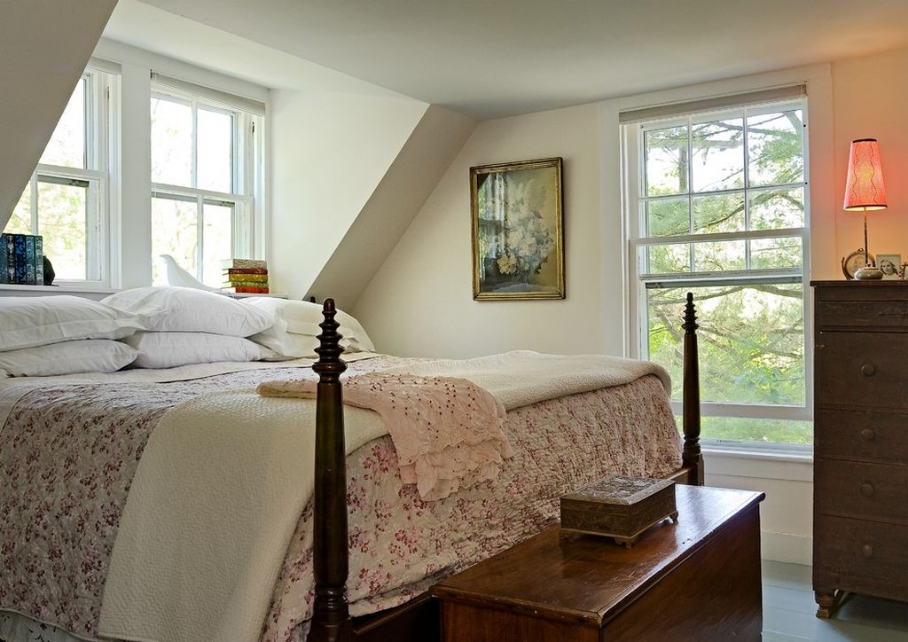 Một phòng ngủ tầng áp mái với cửa sổ thoáng đãng nhiều phía. Bộ chăn ga gối màu trắng phối hợp hoa văn hồng nhỏ xinh đúng chất phong cách đồng quê thanh lịch.