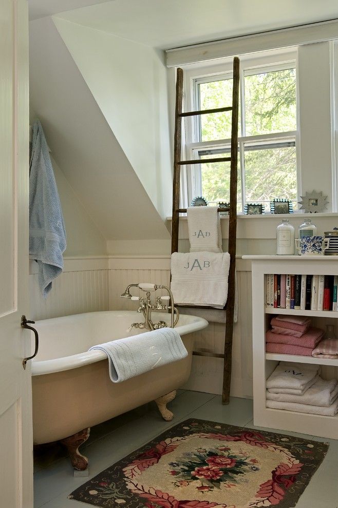 Một phòng tắm với bồn tắm nằm cổ điển, chiếc thang gỗ được tận dụng để làm kệ treo khăn tắm tiện ích. Xung quanh bậc cửa sổ là những khung ảnh nhỏ xinh trang trí đẹp mắt.