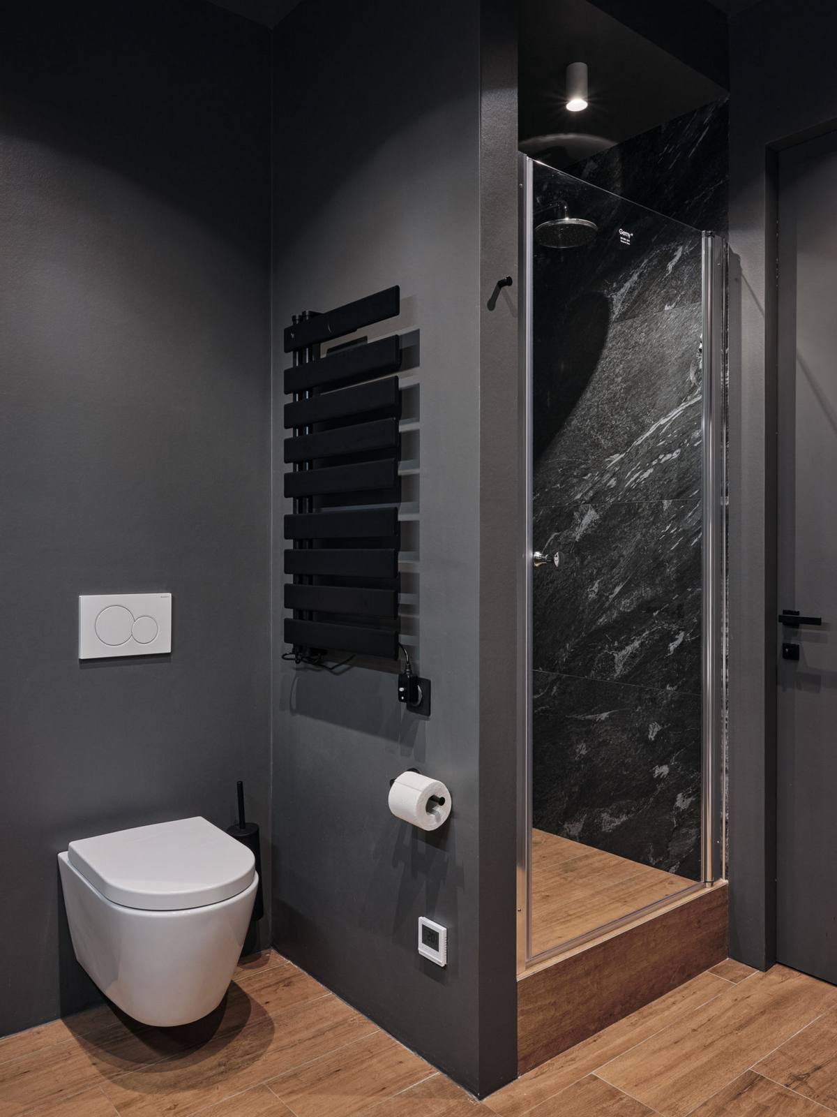 Phòng tắm và nhà vệ sinh sử dụng gam màu xám đậm kết hợp gỗ tự nhiên tạo sự khác biệt hẳn so với những khu vực chức năng còn lại.