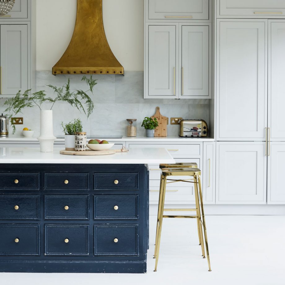 Phòng bếp này lựa chọn cách phối màu tinh tế giữa gam màu trắng sáng hiện đại với sắc xanh denim cổ điển cho đảo bếp thêm nổi bật. Mặt bàn được thiết kế nhô ra một phần để kết hợp với hai chiếc ghế kim loại mạ vàng đồng làm góc ăn sáng nhỏ gọn.