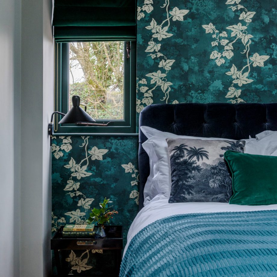 Trang trí phòng ngủ với gam màu xanh ngọc lục bảo và xanh lá cây đậm, mang đến sự kết nối với thiên nhiên, tạo vẻ đẹp yên bình, tĩnh tại. Giấy dán tường, vỏ gối, và cả khung cảnh bên ngoài ô cửa nhỏ như hòa quyện cùng nhau.
