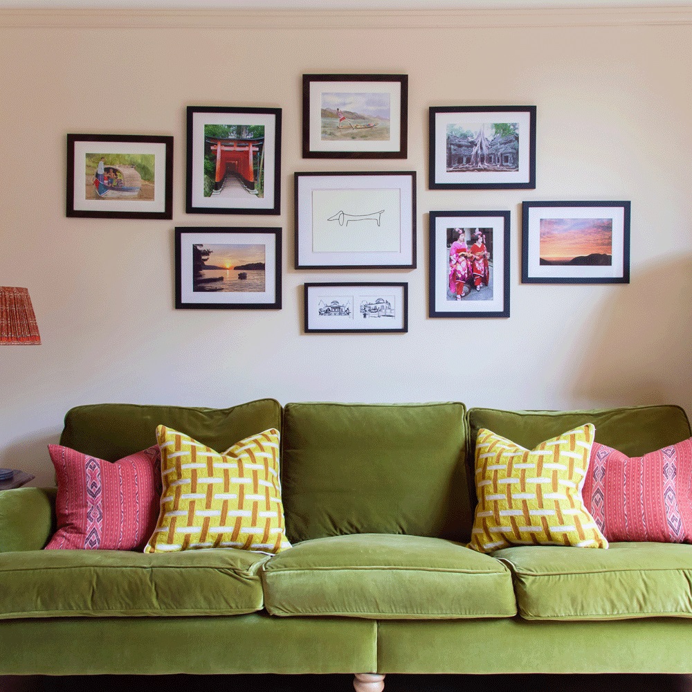 Chiếc ghế sofa màu xanh ô liu được đặt tại trung tâm phòng khách cùng những bức tranh đa dạng chủ đề và vùng văn hóa được trang trí trên bức tường.