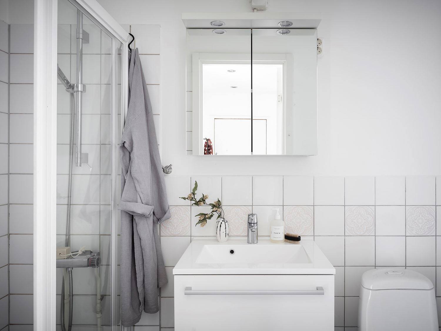 Nếu phòng bếp lựa chọn gam màu gỗ và đen làm bật lên cá tính mạnh mẽ thì phòng tắm lại nhẹ nhàng, thuần khiết với duy nhất gam màu trắng. Phía trên bồn rửa là chiếc tủ lưu trữ cửa ốp gương vừa phản chiếu ánh sáng vừa 'nhân đôi' không gian.