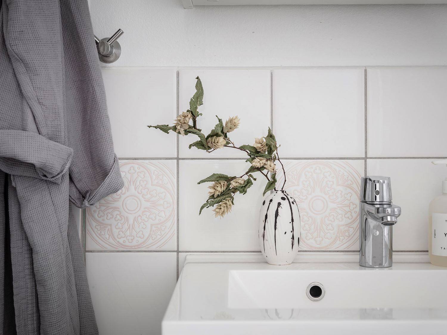 Những chi tiết tinh tế được thể hiện qua hoa văn nhã nhặn của gạch bông ốp tường. Trên bồn rửa tay bằng sứ là chiếc lọ hoa xinh đẹp, dịu dàng, thể hiện sự nữ tính của chủ nhân.