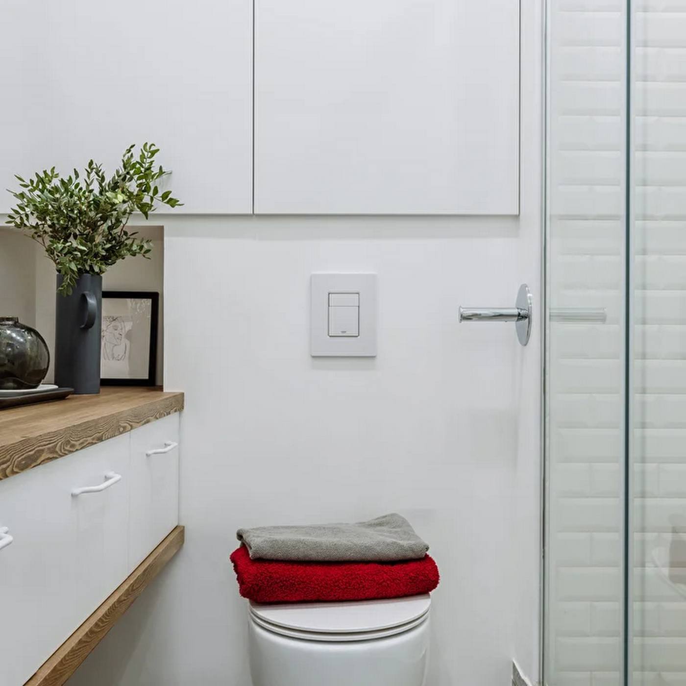 Phòng tắm nhỏ xinh với tủ lưu trữ và bồn toilet gắn tường để giải phóng diện tích sàn. Buồng tắm phân vùng với nhà vệ sinh bằng cửa kính trong suốt.