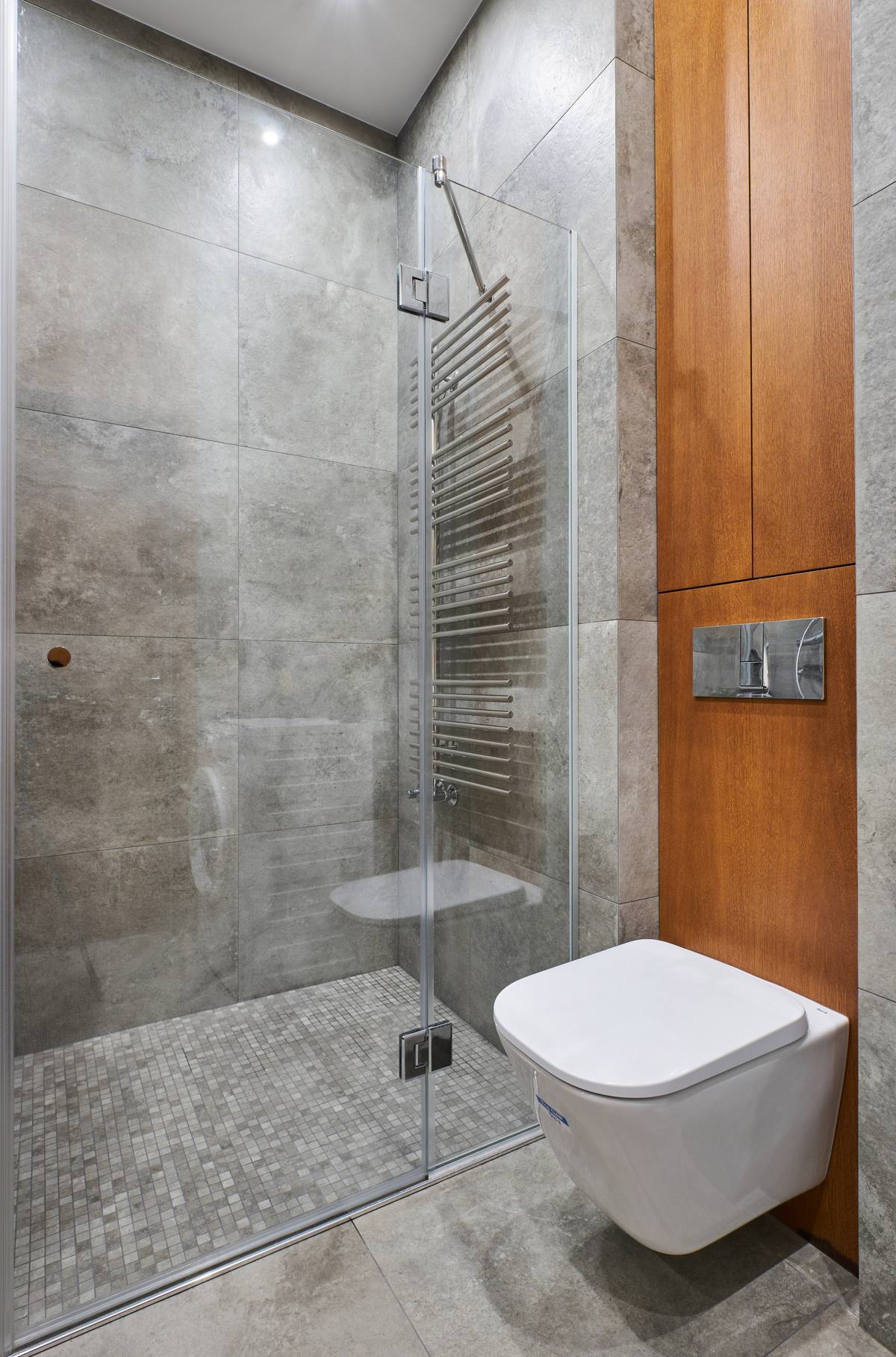 Bồn toilet gắn tường để giải phóng diện tích mặt sàn. Buồng tắm lát gạch sàn ô vuông mini tạo sự phân vùng đồng thời ngăn cách bởi cửa kính trong suốt nên vẫn đảm bảo tính thoáng đãng cho căn phòng.