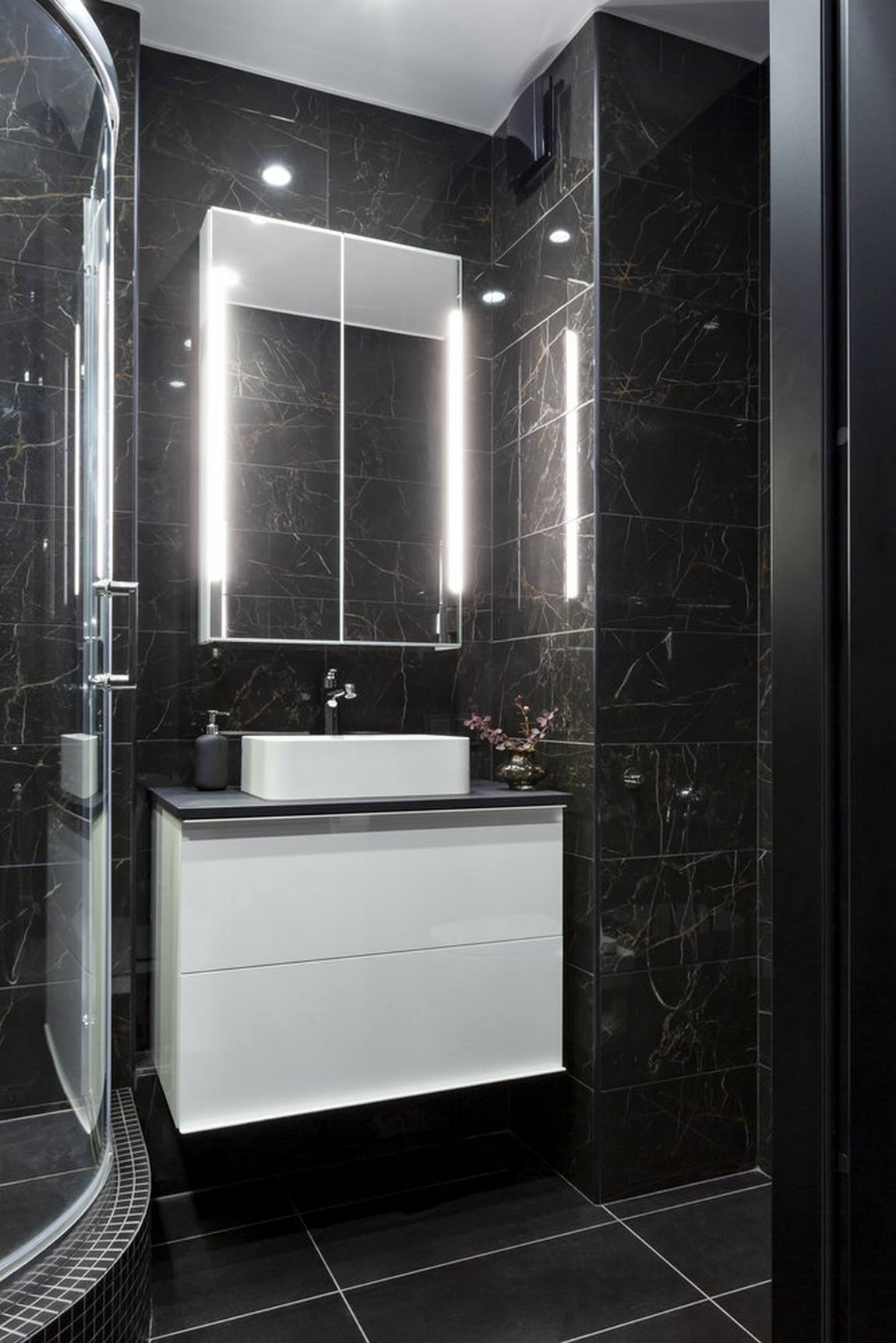 Phòng tắm và nhà vệ sinh được thiết kế với tông màu đen chủ đạo cho cảm giác bí ẩn và lôi cuốn. Bức tường ốp đá đen với đường vân đẹp mắt, tủ lưu trữ kết hợp bồn rửa màu trắng tinh, bên trên là chiếc tủ ốp cửa gương và đèn chiếu sáng tiện ích.