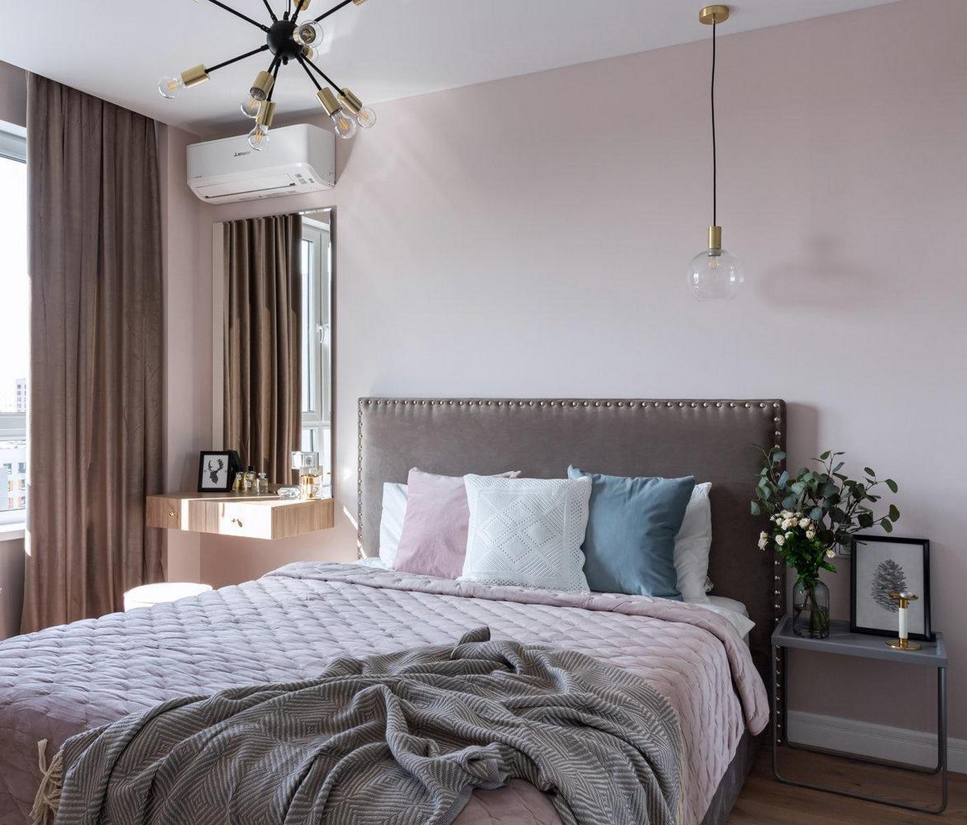 Phòng ngủ của cặp đôi được thiết kế với tông màu be pha hồng, đầu giường màu xám vững chãi. Góc phải cạnh ô cửa sổ đầy nắng là bàn phấn gắn tường kết hợp gương soi cỡ lớn.
