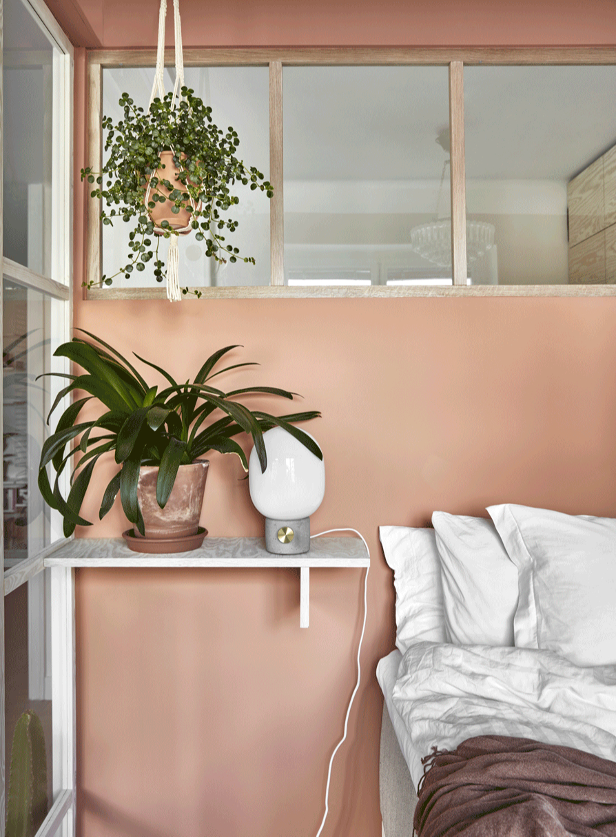Phòng ngủ thuộc sở hữu của 2 nhà thiết kế nội thất Stina Lofgren và Matthias Krisander, với màu sơn tường hồng pastel ngọt ngào. Chiếc kệ gắn tường được tái sử dụng từ mặt bàn gỗ, thay thế cho táp đầu giường phòng ngủ tiện lợi tầm tay với.