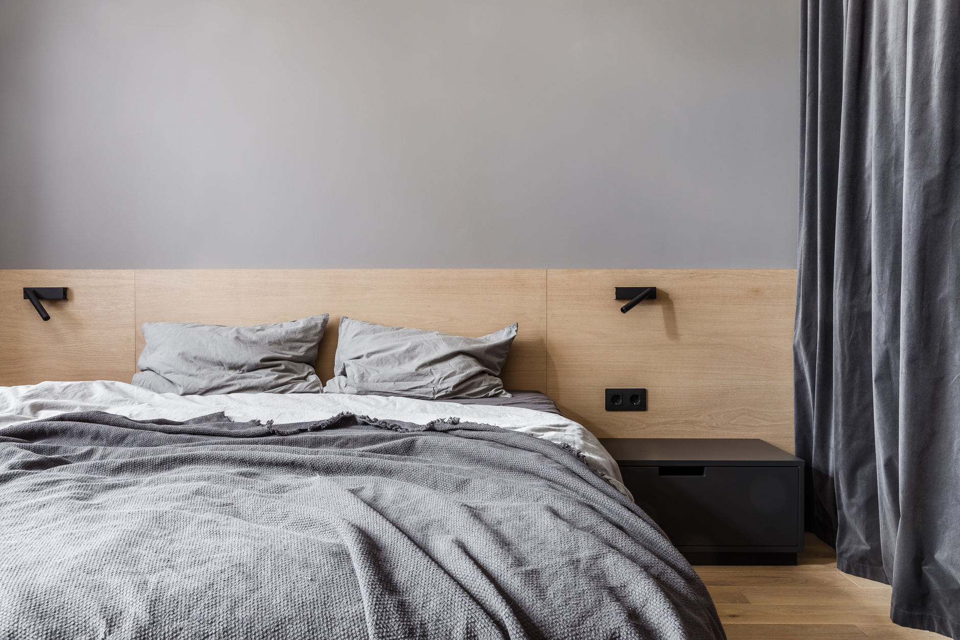 Phòng ngủ phong cách tối giản với gam màu xám vô cùng thanh lịch. Đầu giường bằng gỗ kéo dài toàn bộ chiều ngang bức tường, kết hợp 2 chiếc đèn đọc sách tiện lợi.