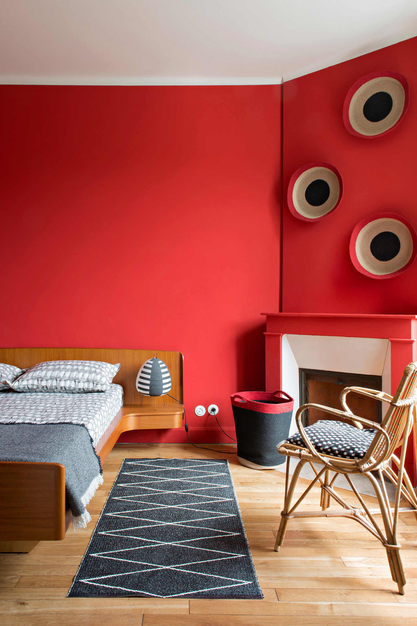 Nếu những phòng ngủ trên lựa chọn gam màu dịu nhẹ thì ở đây, căn phòng bừng sáng với sắc đỏ ấm áp, đầu giường gỗ tích hợp táp đầu giường và ghế mây tuyệt đẹp!