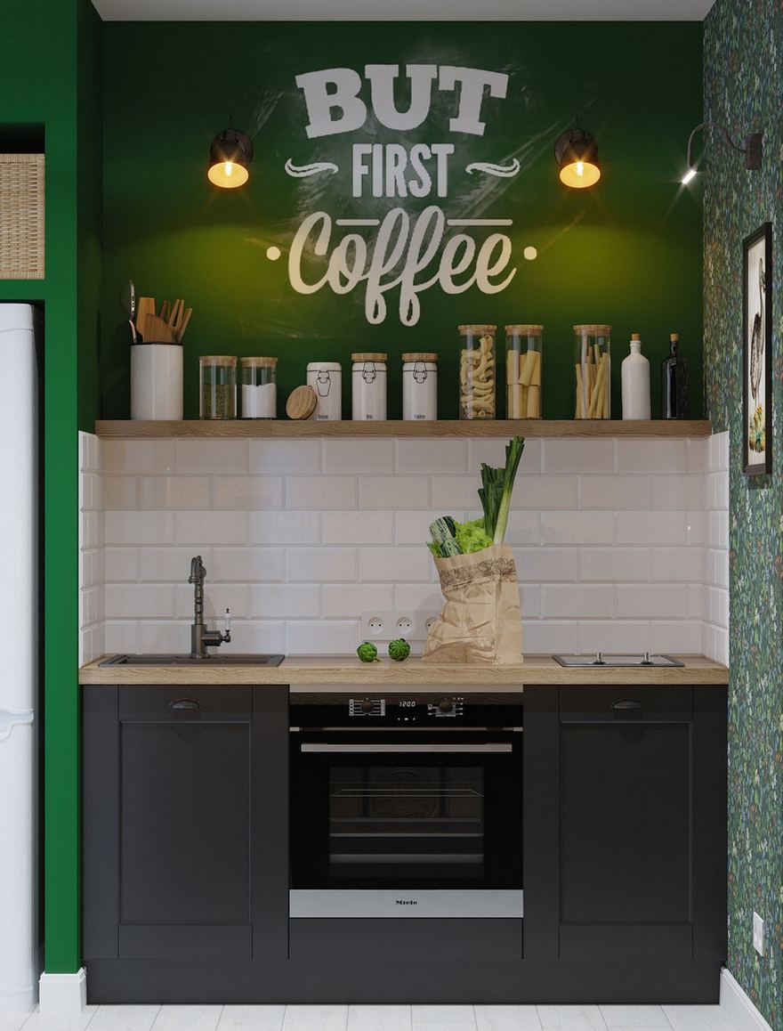 Phòng bếp siêu nhỏ với kiểu chữ I cho lối đi thông thoáng. Tường phòng bếp sơn xanh lá, tủ dưới màu xám đen, backsplash ốp gạch thẻ metro, kệ mở đặt các lọ gia vị gọn gàng, dòng chữ 'But first coffee' được soi chiếu bởi cặp đèn gắn tường đẹp mắt.