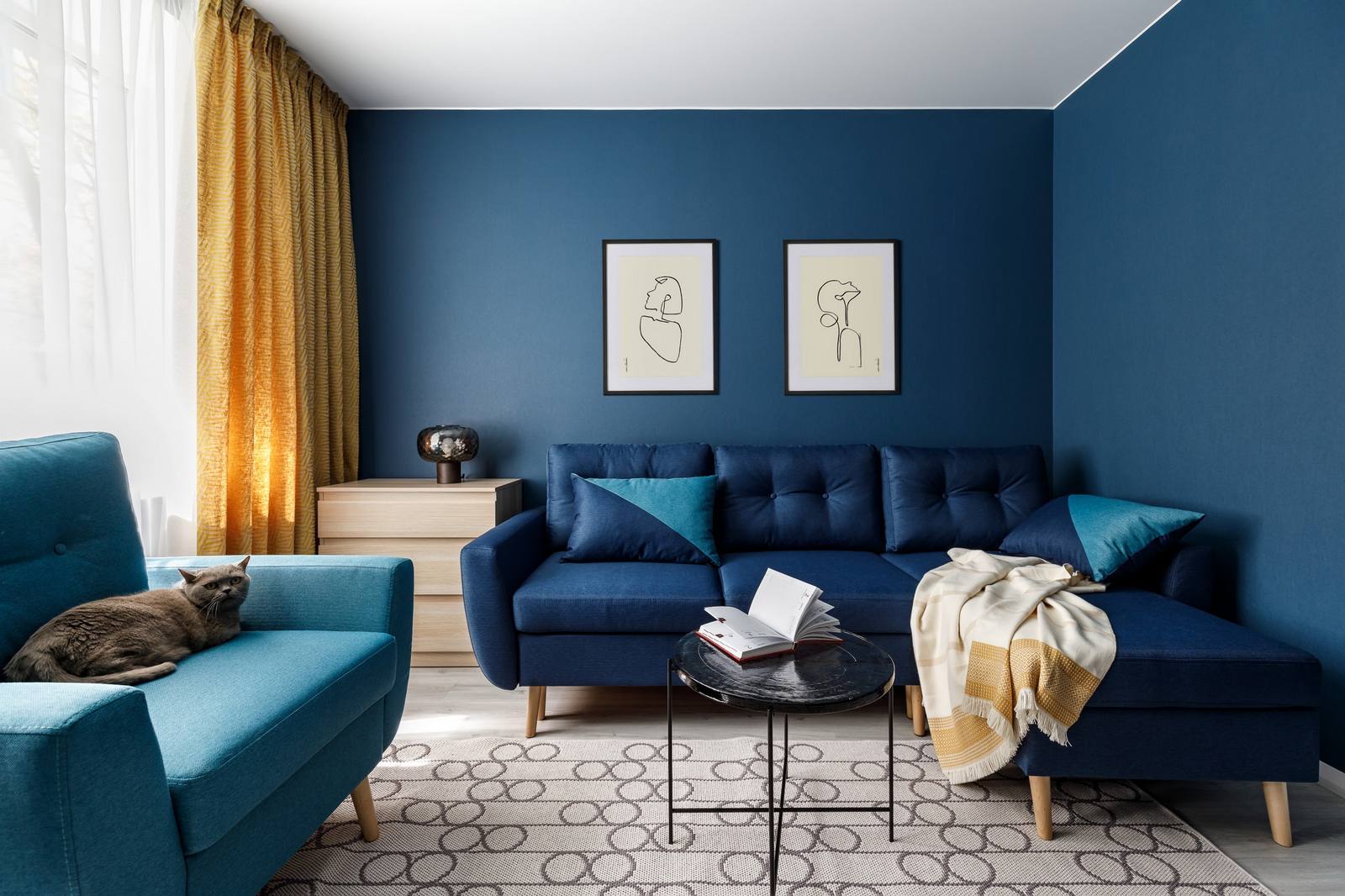 Phòng khách rộng rãi với những tông màu đậm đến nhạt của xanh lam, từ màu sơn bức tường, ghế sofa, vỏ bọc gối tựa, đến ghế bành có màu xanh nhạt hơn. Tất cả tạo nên sự tương phản với sàn và trần nhà sáng màu một cách ấn tượng. 