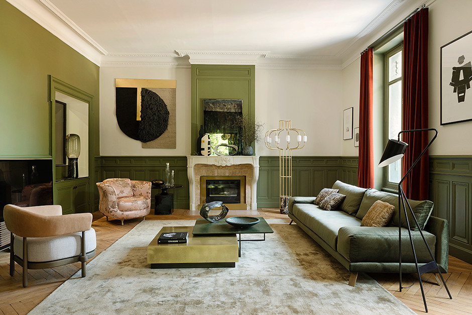 Không gian sang trọng với bức tường sơn màu xanh ô liu gợi vẻ đẹp sinh động của thiên nhiên, cùng với đó là sofa và bàn nước đồng màu ô liu hài hòa. Tấm thảm màu nâu nhạt như màu cát tạo cho phòng khách cảm giác gần gũi với tự nhiên hơn.