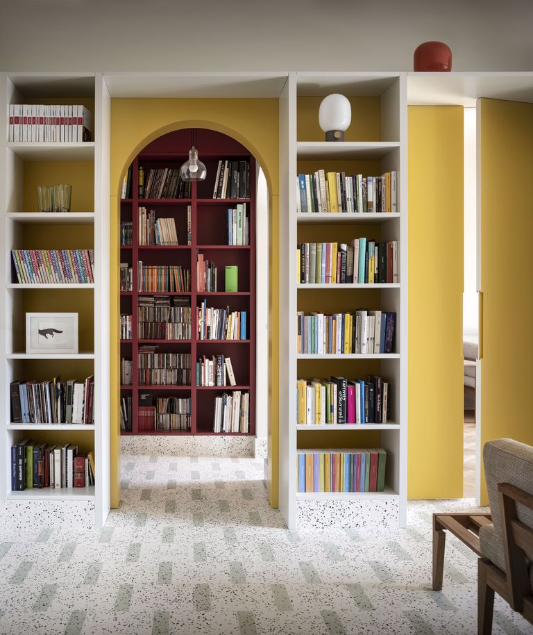 Chủ nhân của ngôi nhà này đã đầu tư hẳn một 'thư viện tại gia' với rất nhiều những cuốn sách được xếp theo chủ đề trông rất gọn gàng, khoa học. Bức tường hình mái vòm sơn vàng, kệ sách màu trắng và đỏ mận tạo nên điểm nhấn vô cùng nổi bật.
