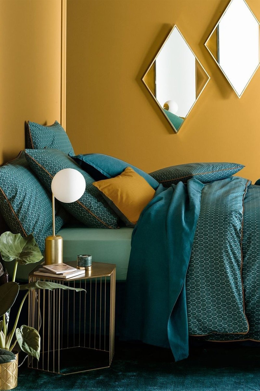 Nếu phòng ngủ ở trên nhẹ nhàng, lãng mạn với gam vàng pastel thì không gian này lại thời trang và cá tính khi kết hợp màu vàng mù tạt với sắc xanh ngọc lục bảo. Cùng với nội thất bằng kim loại mạ vàng đồng như táp đầu giường, đèn bàn, khung gương,... tạo nên sự sang chảnh tuyệt đối.