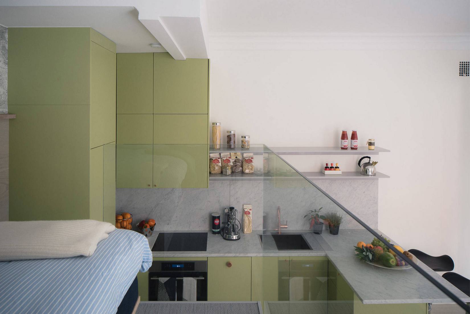 Hình ảnh phòng bếp được chụp từ không gian phòng ngủ cho thấy hệ tủ lưu trữ thiết kế kịch trần nhằm tối ưu hóa chiều cao trần nhà.