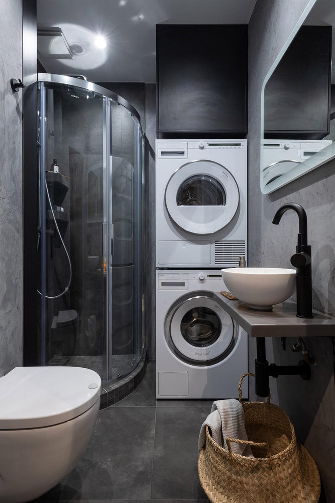 Vì phòng tắm có diện tích rất nhỏ và hẹp nên máy giặt và máy sấy được xếp chồng lên nhau để tiết kiệm không gian, phía trên cùng là chiếc tủ sơn đen đầy bí ẩn.