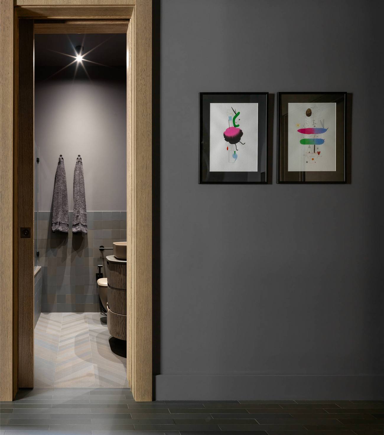 Khu vực phòng tắm và nhà vệ sinh được bố trí ngay tại hành lang vào nhà, ở góc trái. Bên ngoài là cửa gỗ, trên tương trang trí 2 bức tranh để giảm đi sự đơn điệu cho bức tường màu xám.
