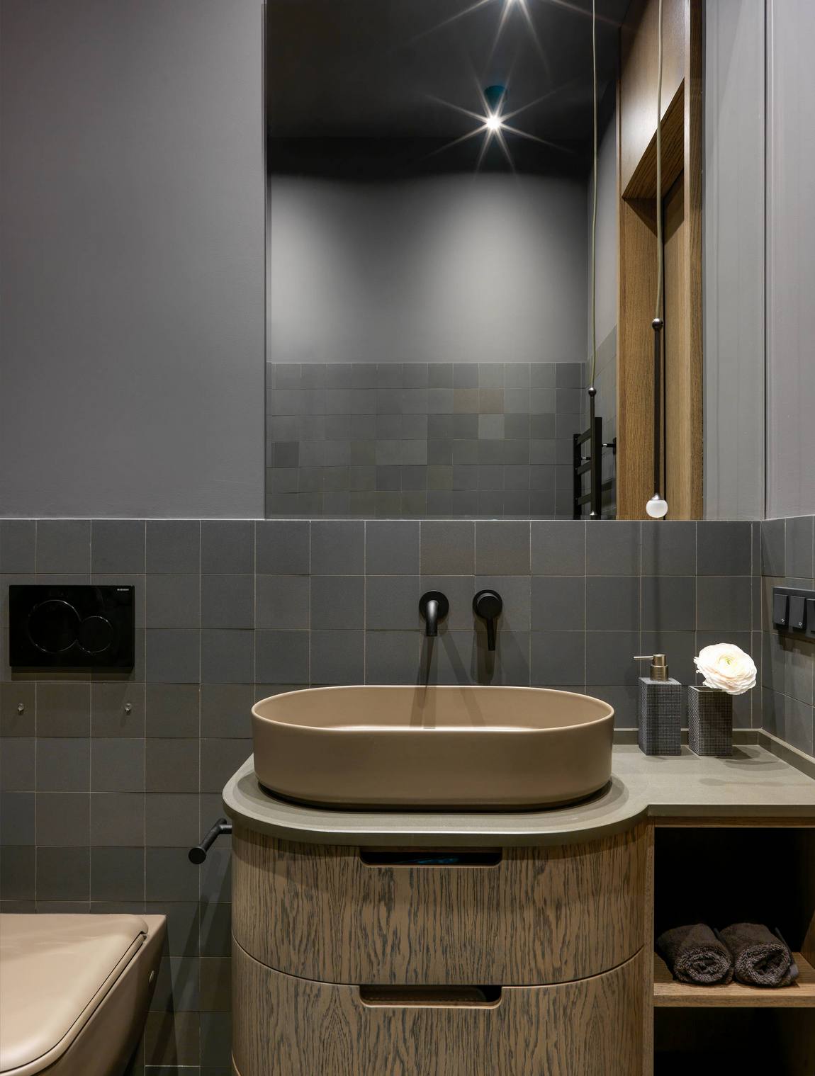 Phòng tắm có thiết kế kiểu cổ điển với tủ lưu trữ kết hợp bồn rửa gam màu nâu và kiểu ngăn kéo truyền thống. Bên trên là tấm gương cỡ lớn giúp phản chiếu ánh sáng từ đèn trần cho căn phòng thoáng sáng hơn.