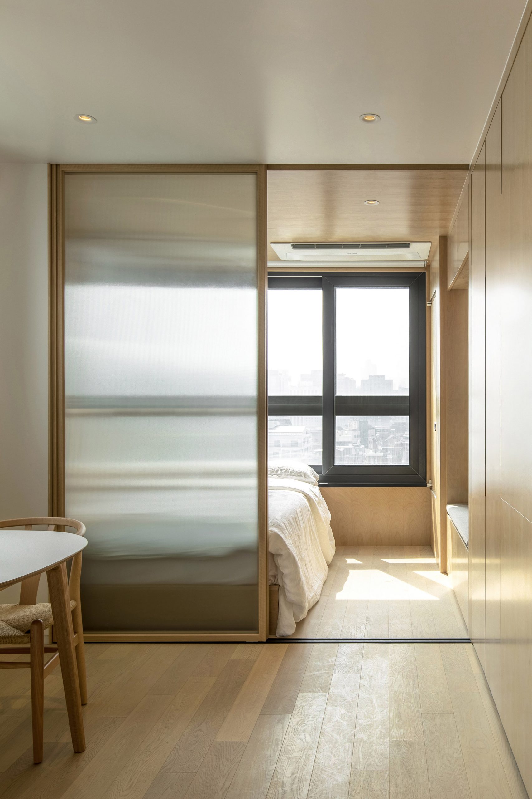 Hình ảnh phòng ngủ trong căn hộ cho thuê siêu nhỏ (mỗi phòng chỉ từ 16m² - 23m²) tại Seoul, Hàn Quốc. Các vách ngăn kính trượt phân chia các phòng với cửa kính mờ nhằm tăng thêm sự riêng tư giữa phòng ngủ và không gian sinh hoạt chung.