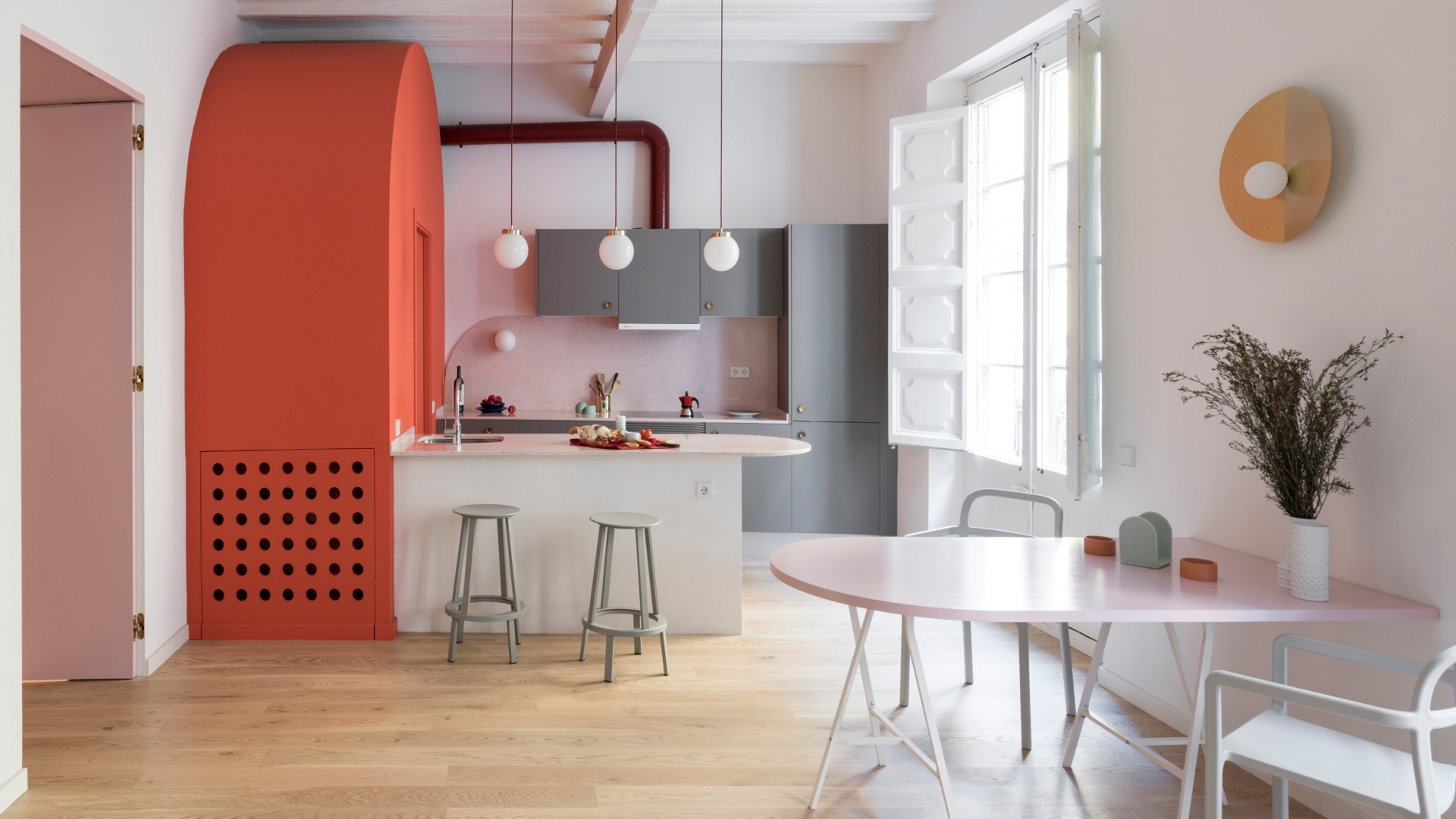 Colombo and Serboli Architecture đã thiết kế phòng bếp có không gian mở tươi sáng cùng nội thất sắc màu trẻ trung như cam, hồng phấn,... Ngoài bàn ăn chính, NTK còn tích hợp quầy bar nối liền tủ lưu trữ màu cam với đường cong bo tròn mềm mại.