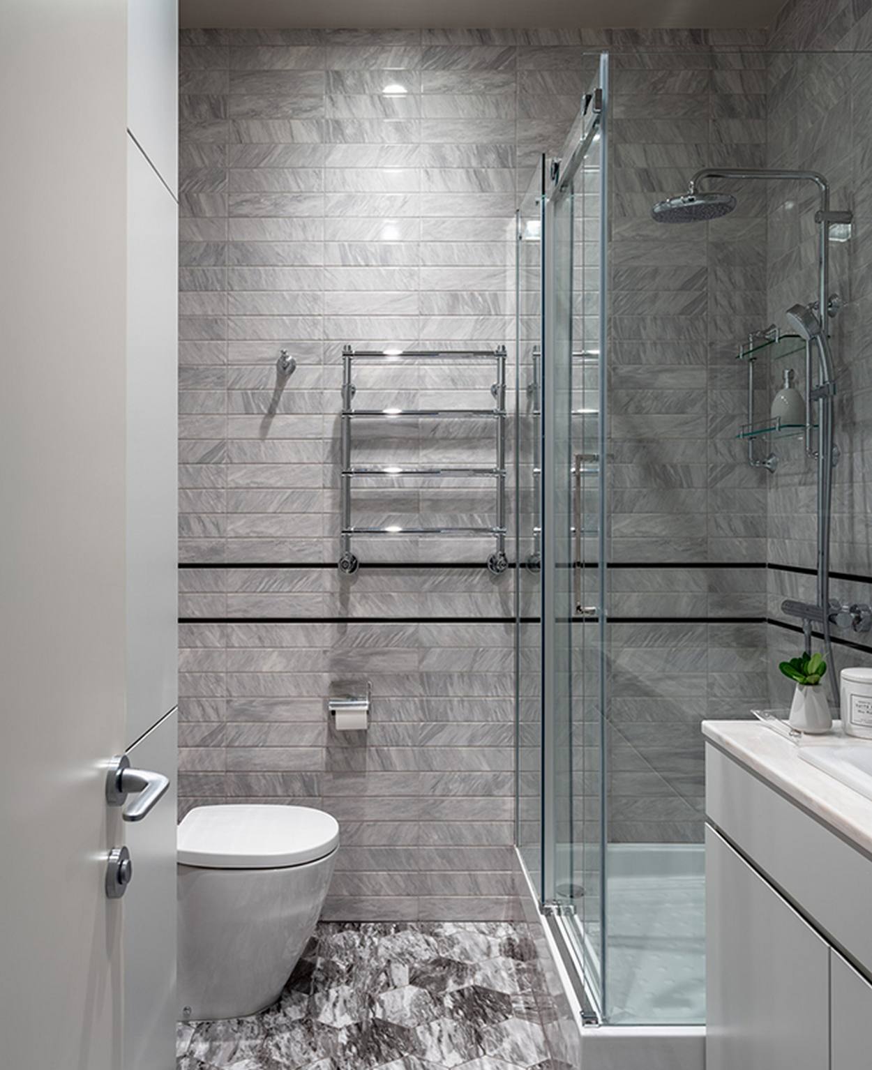 Buồng tắm được thiết kế nâng sàn, đối diện với nhà vệ sinh và được phân vùng bằng cửa kính trong suốt để không gây 'cản trở' thị giác người nhìn. Sàn gạch lục giác gợi nhớ đến khu vực lối vào mà chúng ta tham quan khi vừa đến căn hộ.