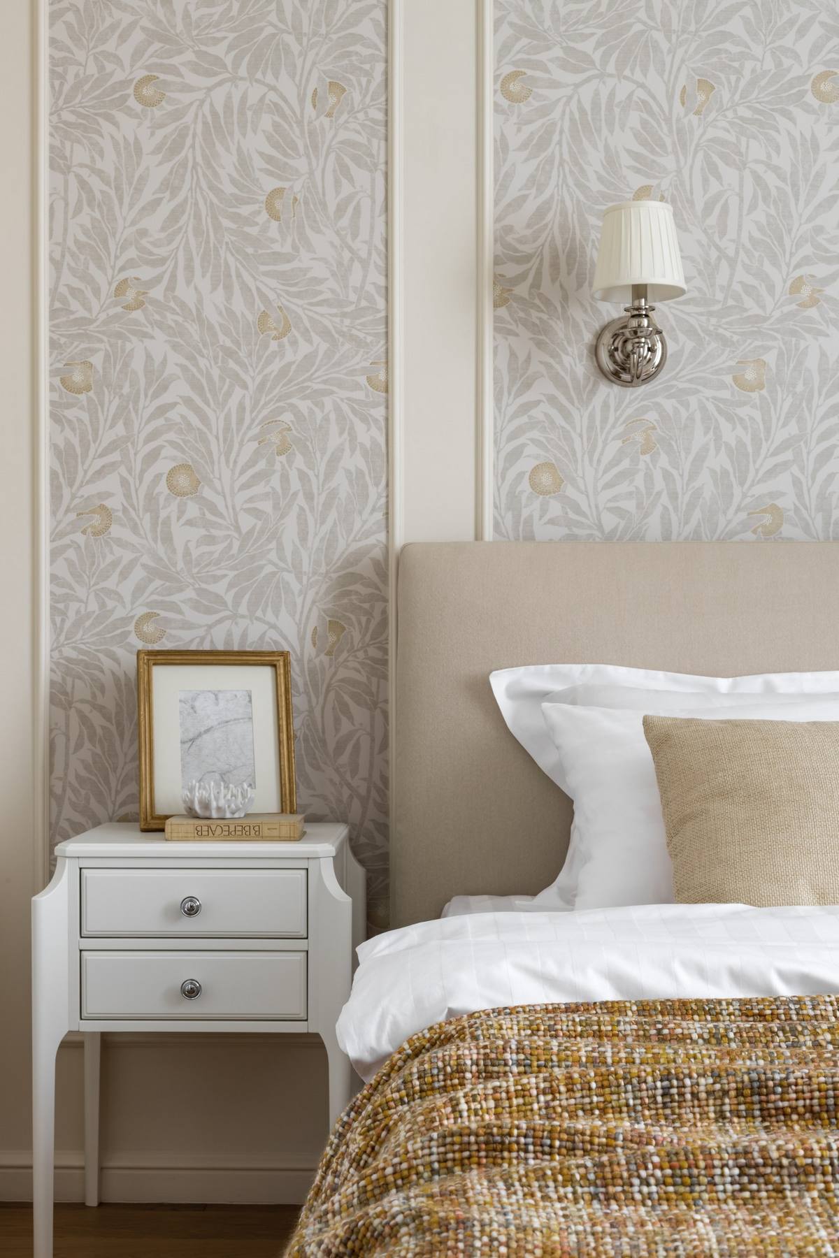 Phòng ngủ của cặp đôi được thiết kế đơn giản với giấy dán tường hoa văn trang nhã. Táp đầu giường cũng như đèn chiếu sáng gắn tường cũng được chọn lựa tinh tế cùng cách sắp đặt đối xứng.