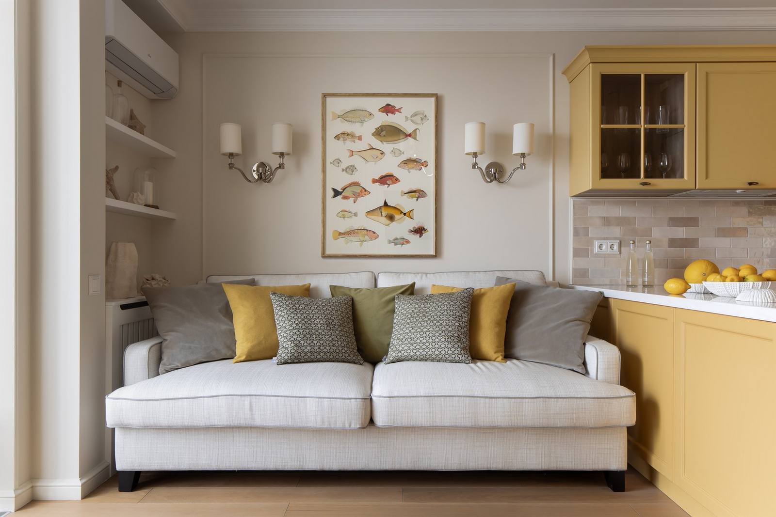 Phòng khách sử dụng gam màu be để sơn tường, sàn nhà lát gỗ tự nhiên cho cảm giác ấm áp. Chiếc ghế sofa màu trắng êm ái, rộng rãi với rất nhiều những chiếc gối tựa màu vàng và xám.