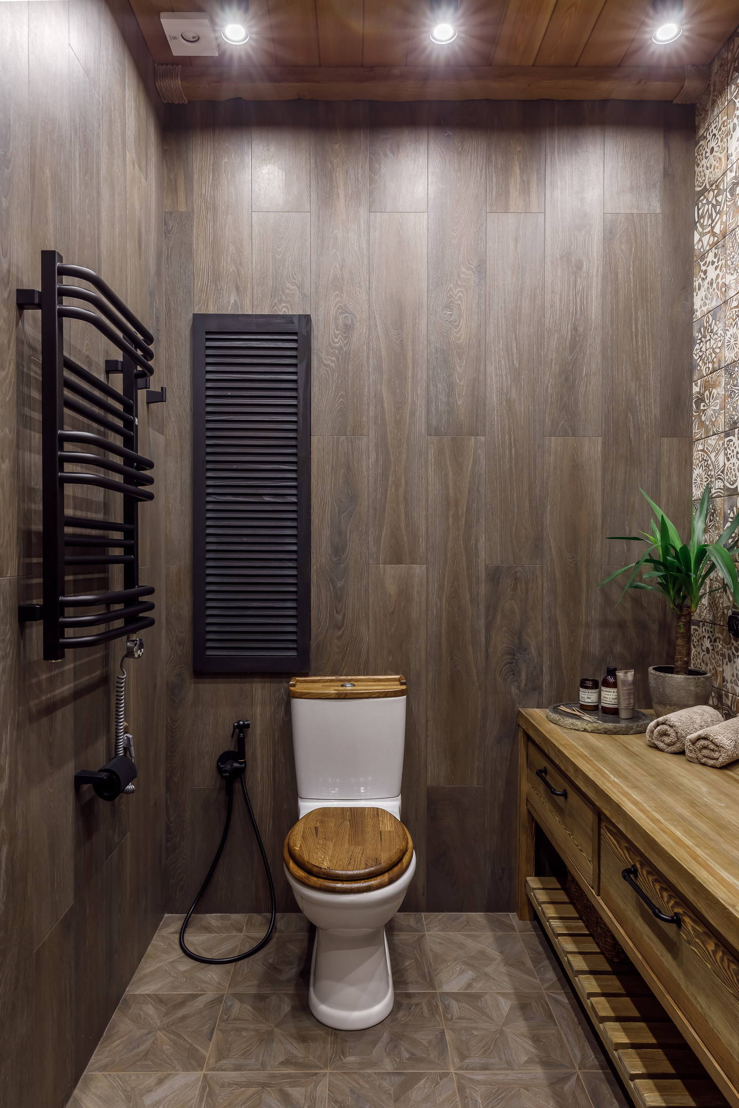 Bức tường của 2 khu vực phân biệt rõ ràng: Tường gỗ cho nhà vệ sinh và tường ốp gạch bông cho bồn rửa tay và buồng tắm.