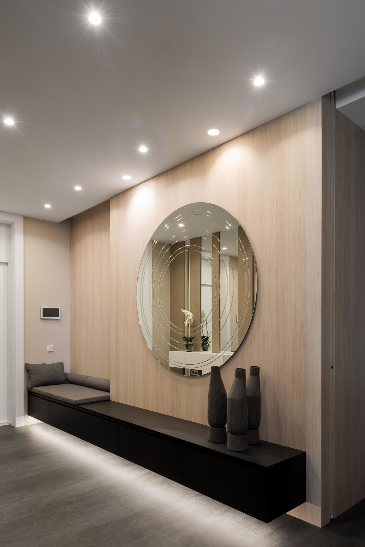 Hành lang tuyệt đẹp của căn hộ do Fedorova Architects thiết kế, với vật liệu gỗ sáng màu cùng băng ghế nghỉ chân kéo dài toàn bộ bức tường. Phía trên là tấm gương tròn cỡ lớn phản chiếu ánh sáng từ hệ thống đèn trần cho lối vào đẹp lung linh.