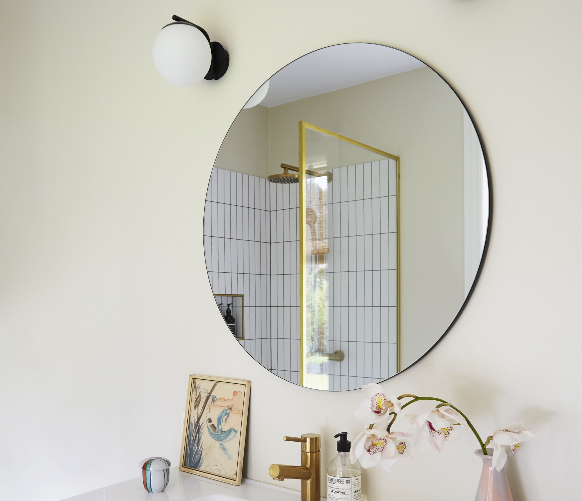 Tấm gương tròn trên bồn rửa cũng góp phần phản chiếu ánh sáng từ ô cửa cho không gian bừng thêm sức sống. 
