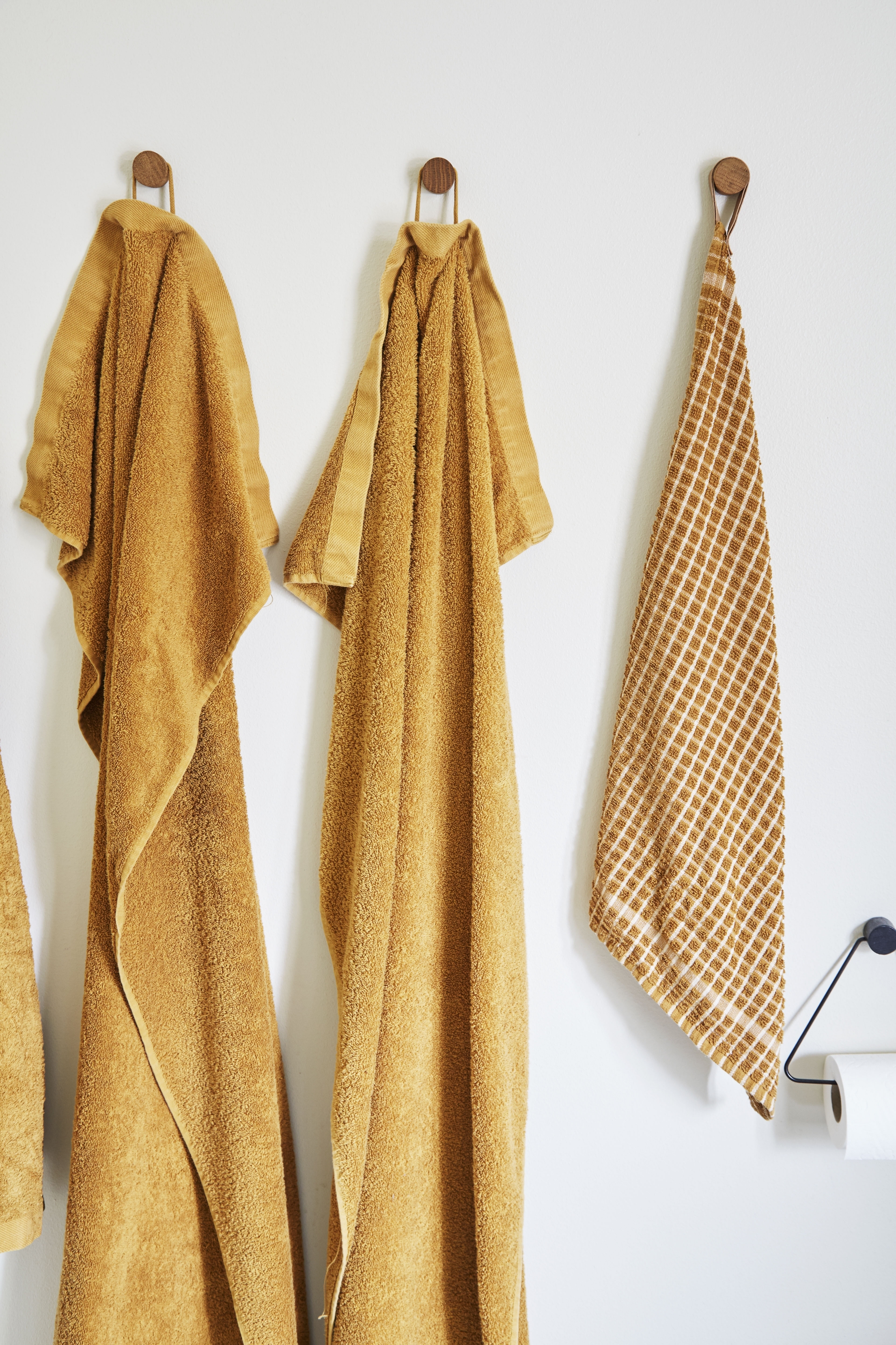 Màu khăn và áo choàng tắm cũng được lựa chọn đồng màu cam gạch nổi bật., treo trên những núm gỗ nhỏ thay cho kệ nhiều móc bằng inox nhàm chán.